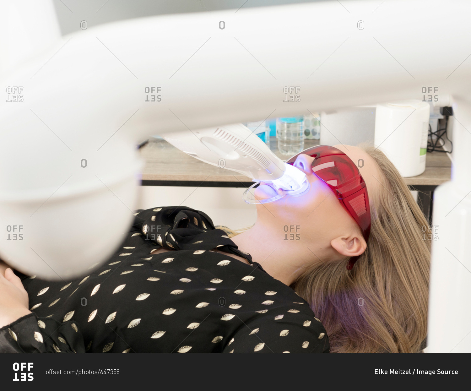 Young woman in dentist chair, having teeth whitened