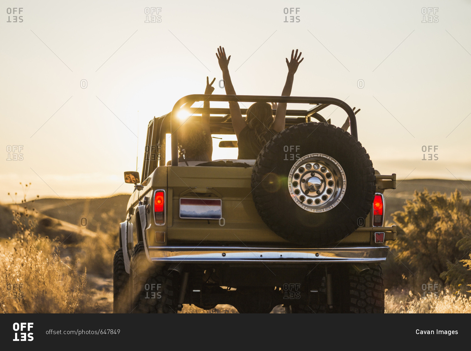 Rear view of female friends gesturing while traveling in off-road vehicle against sky
