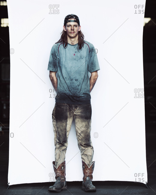 Portrait of messy young worker standing against backdrop in industry