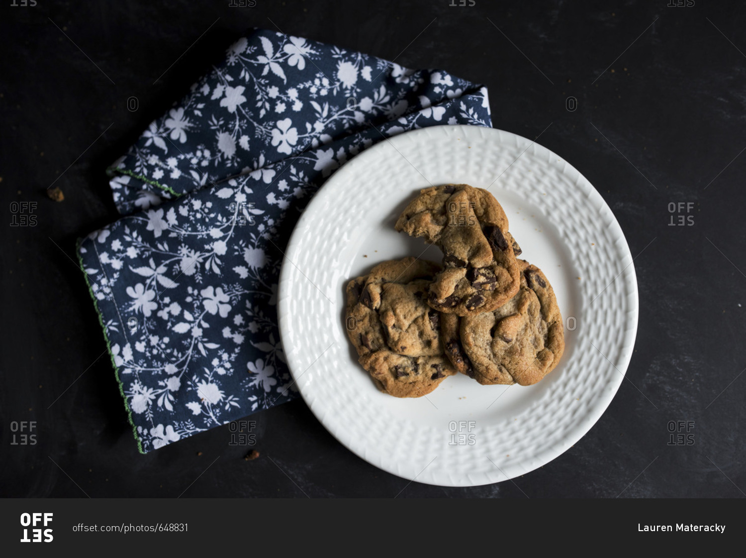 Freshly baked chocolate chip cookies on a plate with a bite missing from one
