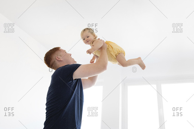 Low angle view of father lifting daughter while standing at home