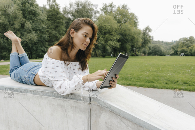 Young woman using lying in a skate park using a tablet