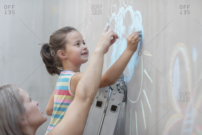 Mother and daughter drawing with chalk on a concrete wall