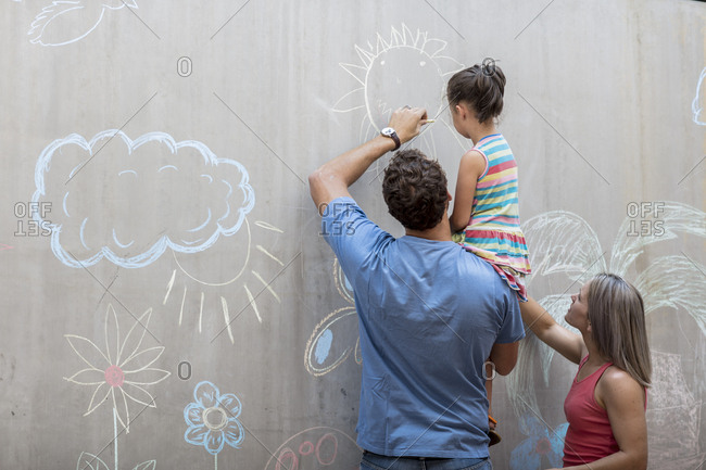 Family drawing colorful pictures with chalk on a concrete wall