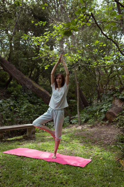 Woman practicing yoga in garden on a sunny day