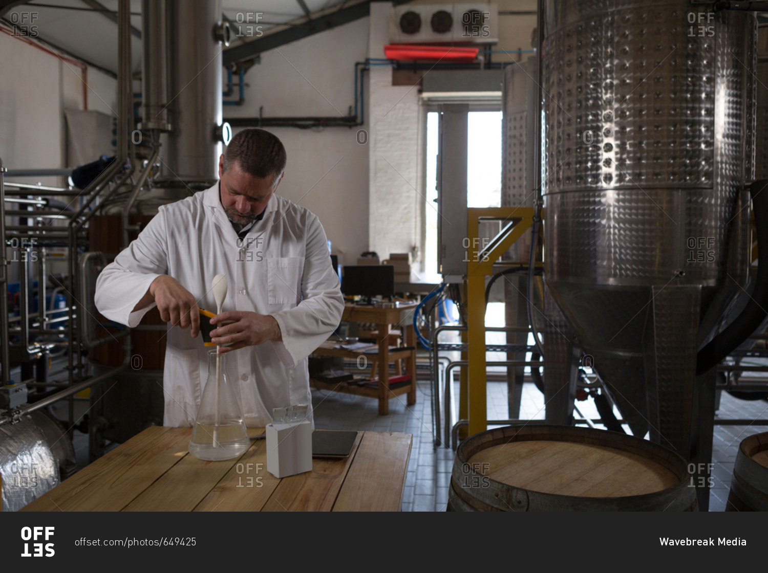 Male worker checking quality of gin in factory