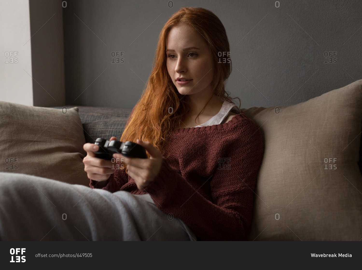 Happy young woman playing video game at home - a Royalty Free