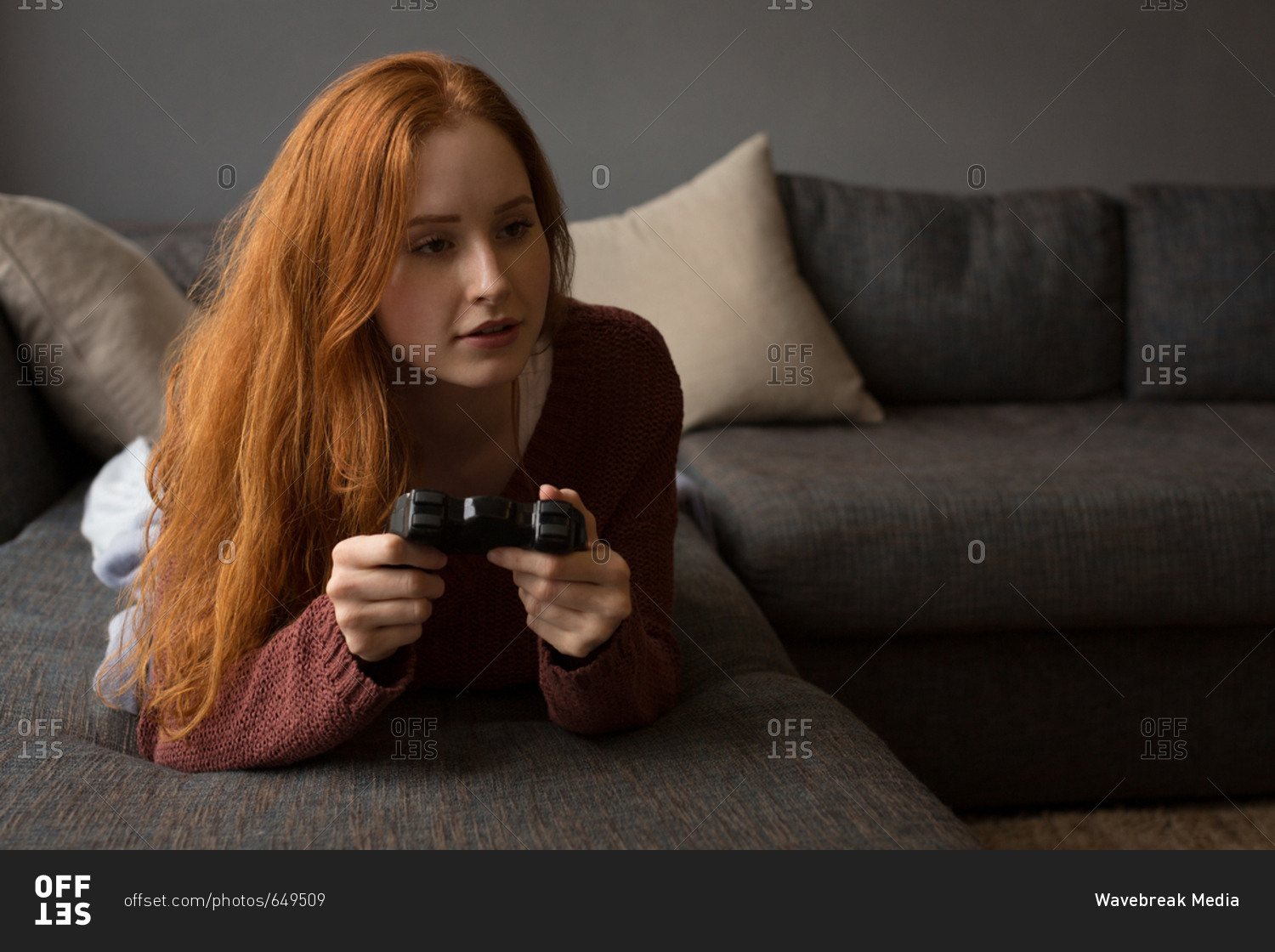 Happy young woman playing video game at home - a Royalty Free