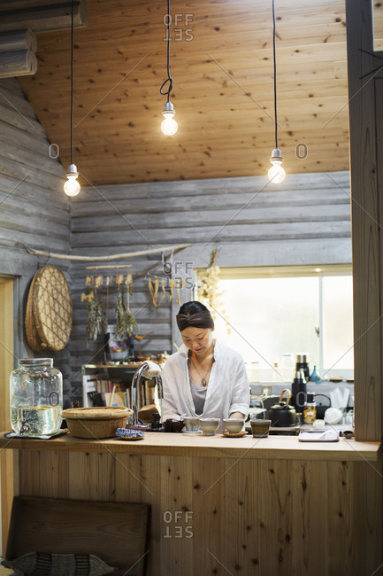 Woman standing in a kitchen, cleaning dishes, smiling