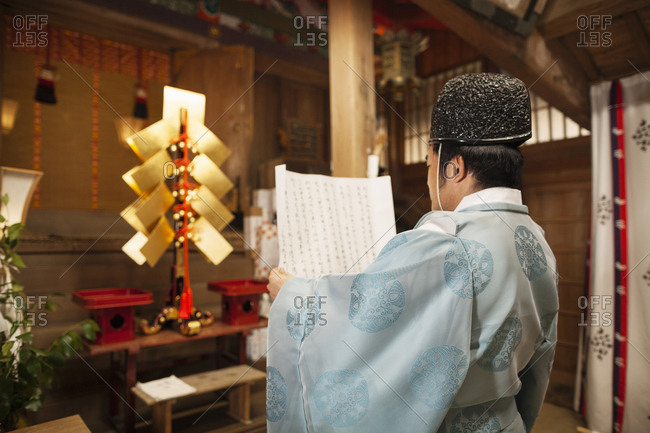 Rear view of priest holding scroll at Shinto Sakurai Shrine, Fukuoka, Japan