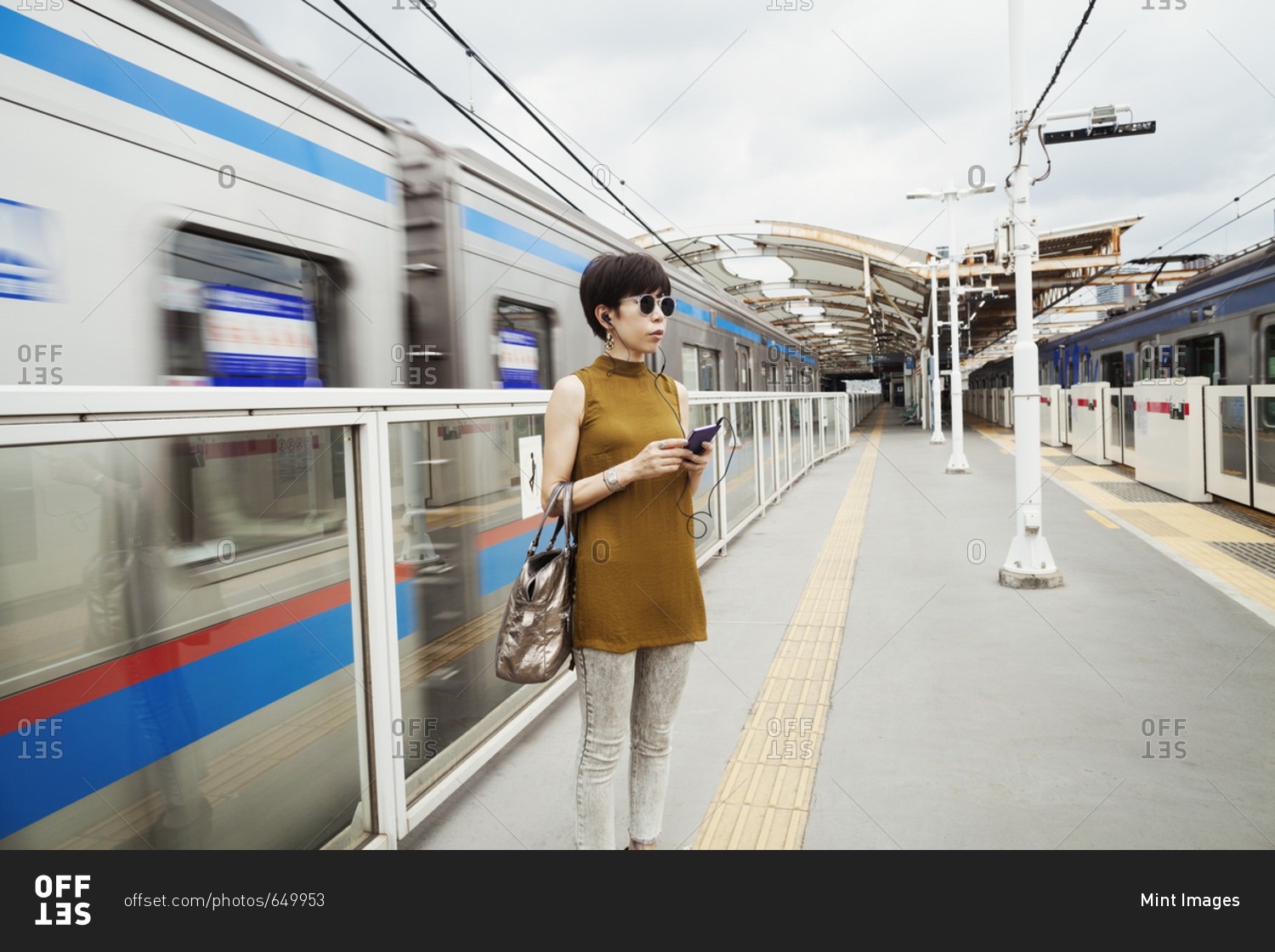 Woman wearing sunglasses standing on the platform of a subway station, Tokyo commuter