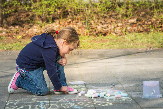 Blonde girl drawing with chalk on sidewalk, Munich, Bavaria, Germany