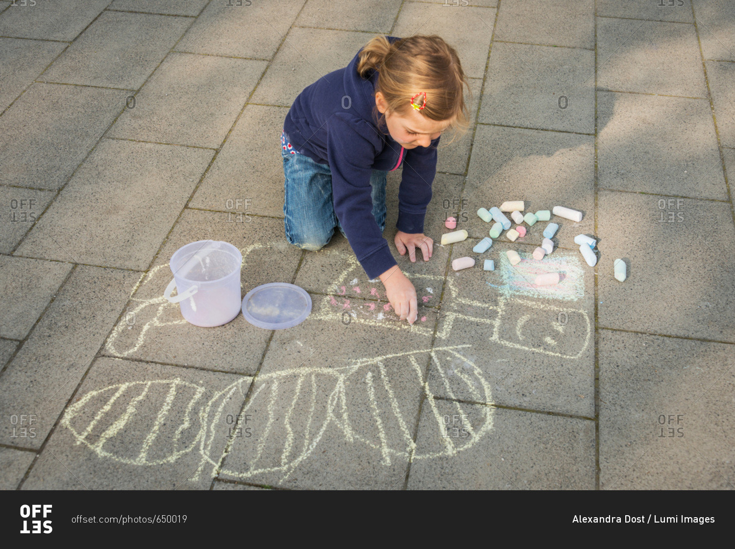 Blonde girl drawing with chalk on sidewalk, Munich, Bavaria, Germany