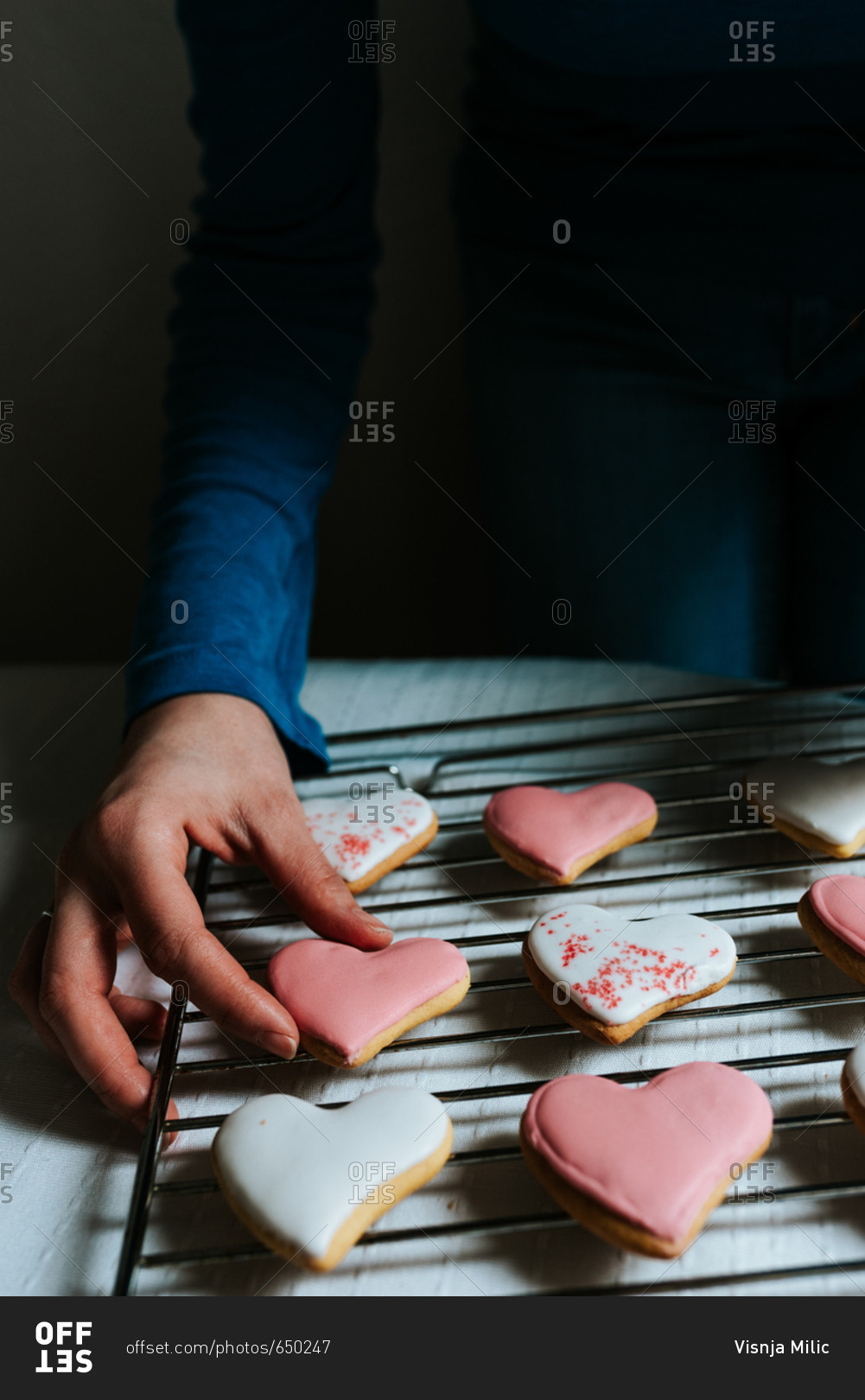 Hands holding one heart-shaped gingerbread cookie