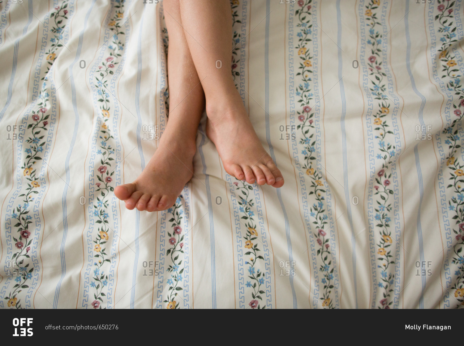 Pair of little feet crossed on bed