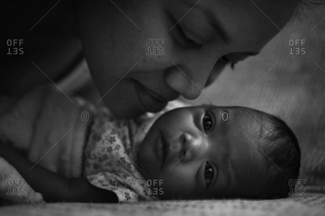 Mother leaning in to kiss infant daughter