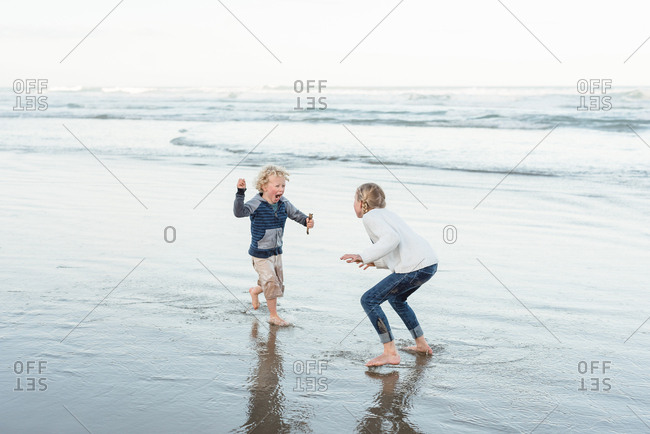 Two siblings playing on the coast of Hawke's Bay, New Zealand