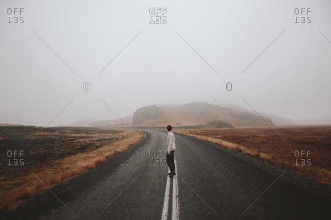 Boy standing in middle of road in foggy weather, Iceland