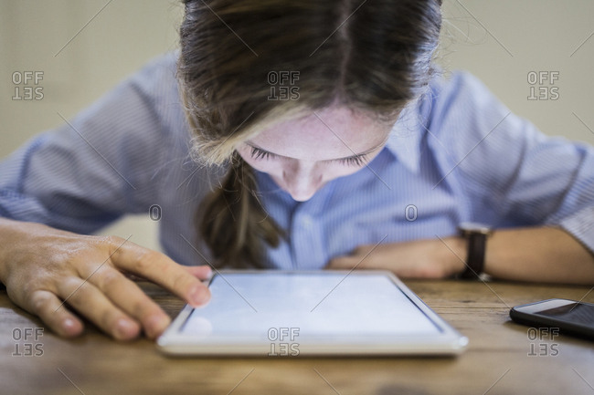 Close-up of woman bending over tablet at desk