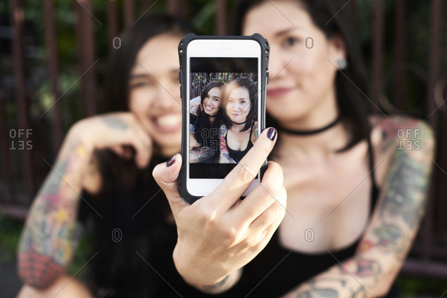 Woman holding cell phone with selfie of herself with her lesbian partner