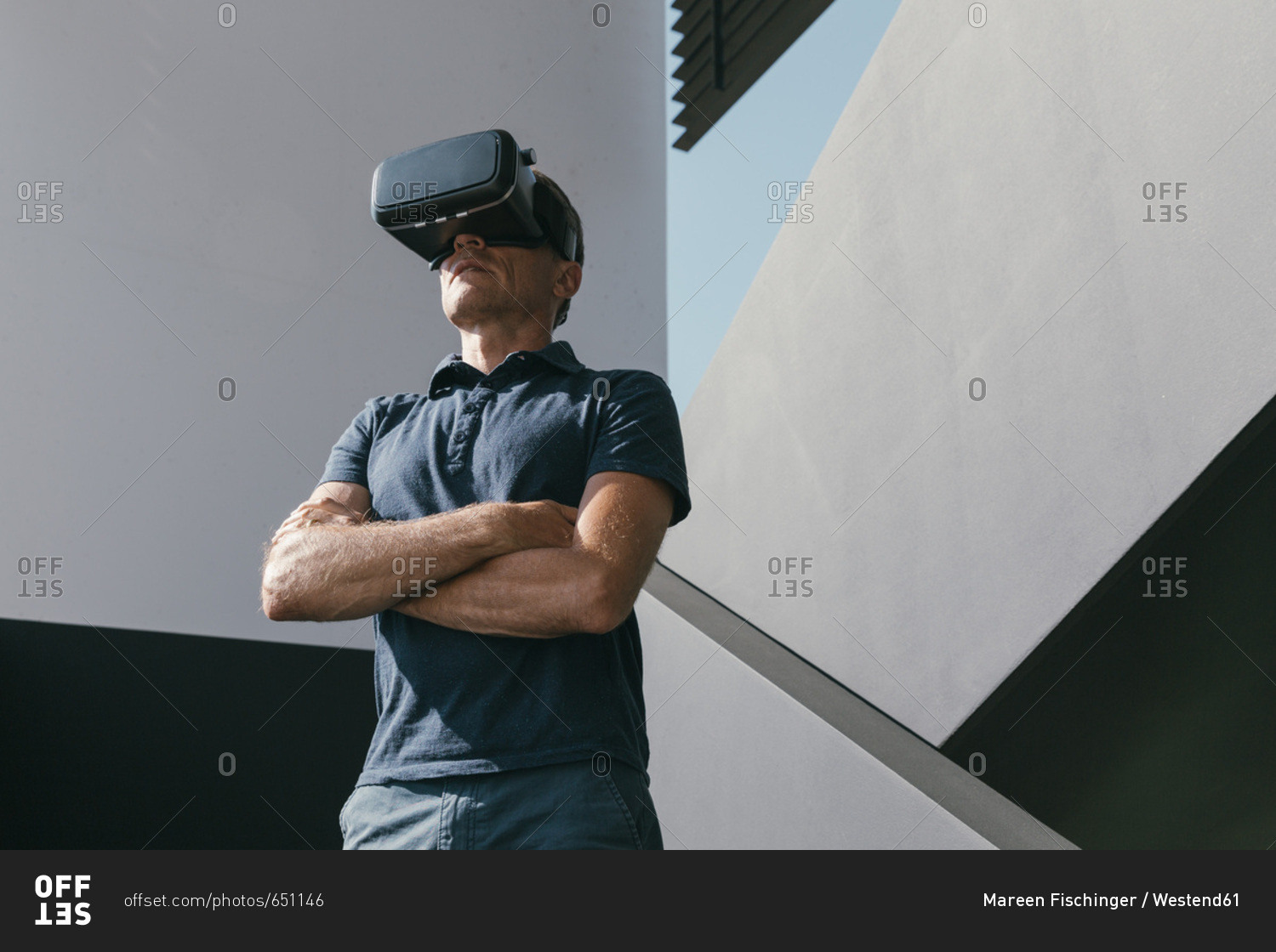 Mature man wearing VR glasses standing between walls of modern architecture