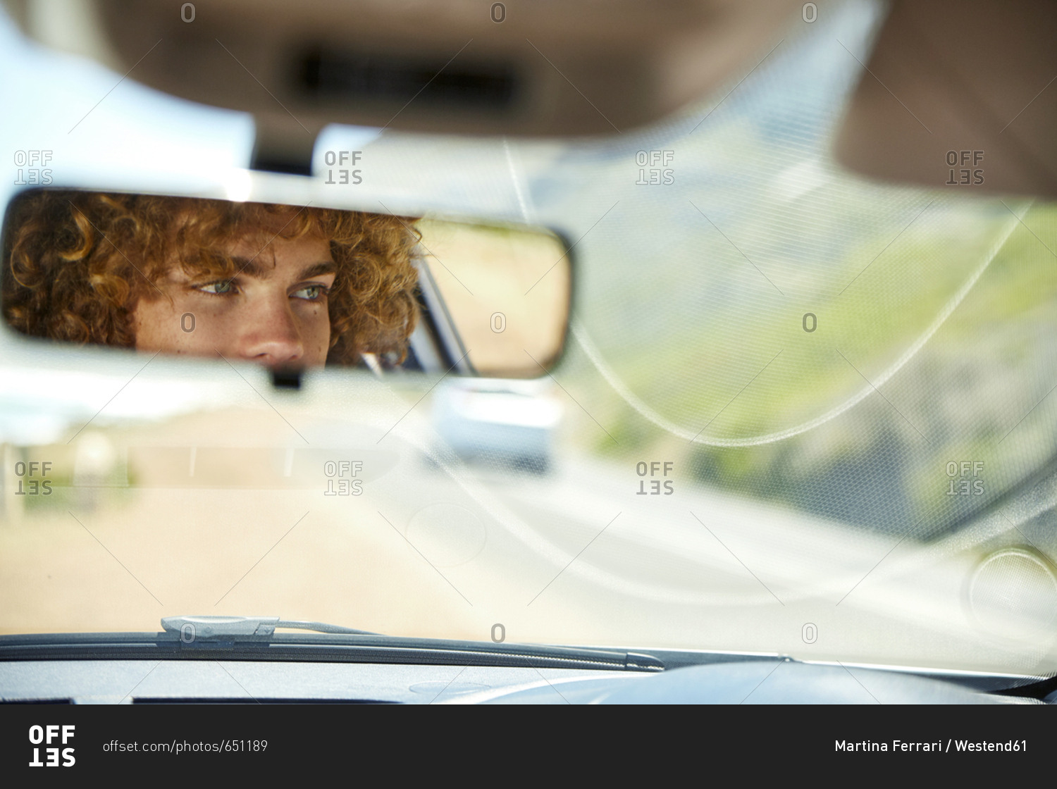 Young man driving car- rear view mirror- mirrored