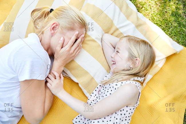 Happy girl with mother lying on a blanket
