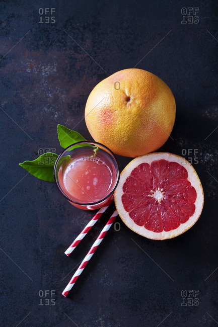 Whole and sliced Pink Grapefruit- leaves- straws and glass of grapefruit juice