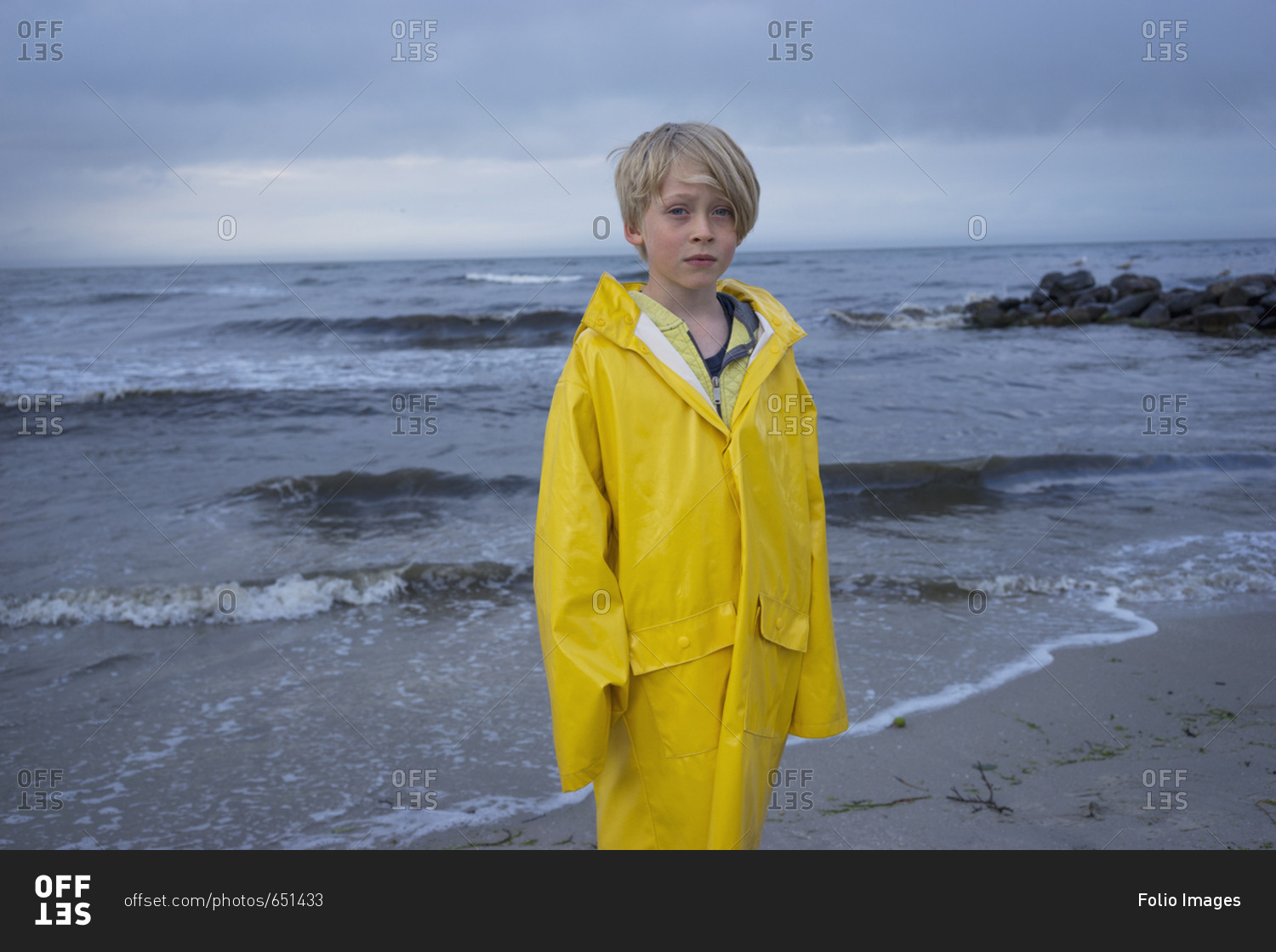 A young boy at the beach in wet weather gear