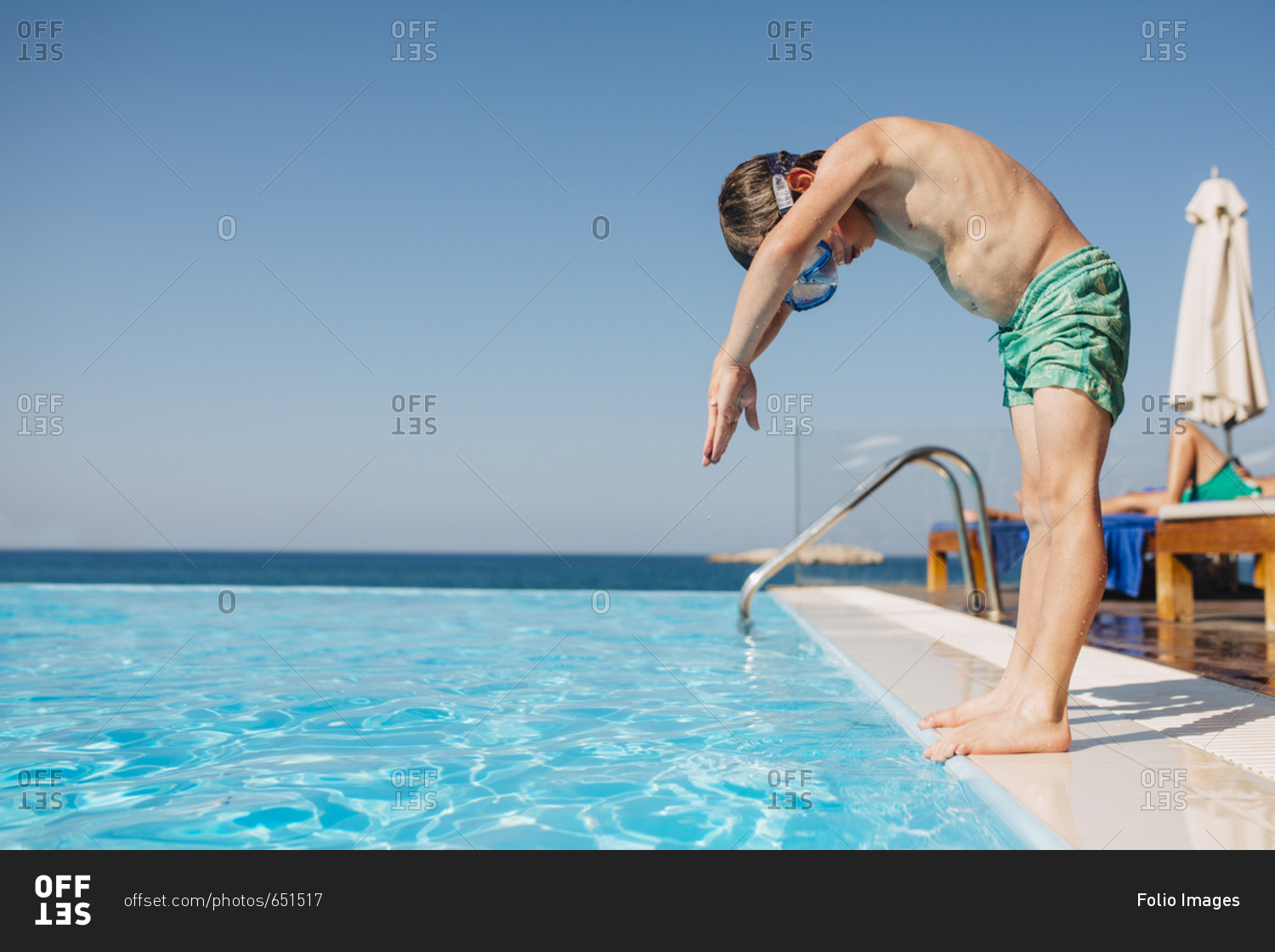 A young boy preparing to dive into a pool stock photo - OFFSET