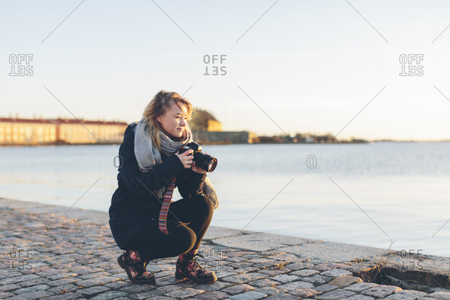 Woman holding a camera by the sea