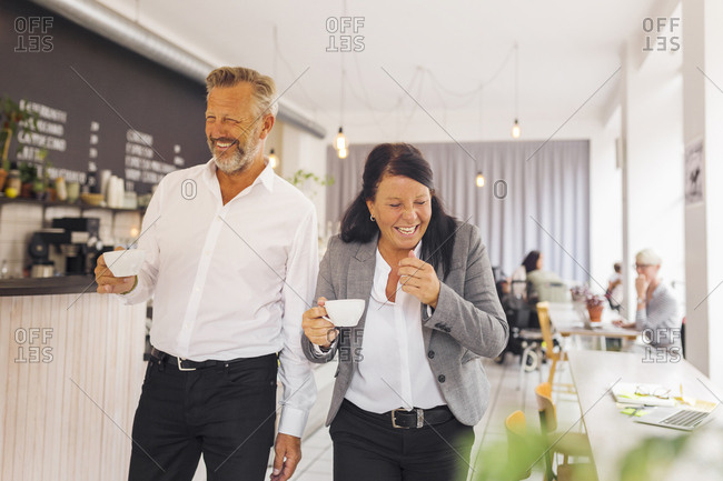Senior man and mature woman laughing in cafe