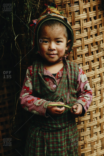 Langtang, Nepal - November 4, 2011: Portrait of a young Tamang girl standing against large woven container
