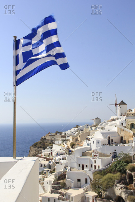 Greek Flag waving by sea against town and clear sky