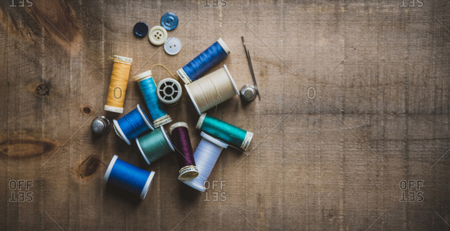 High angle view of colorful spools with thimbles and buttons on wooden table at workshop
