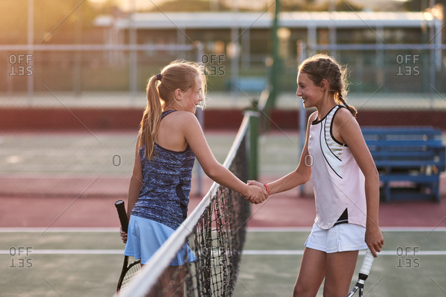 Opponents shake hands after their tennis match game, display of sportsmanship and friendship