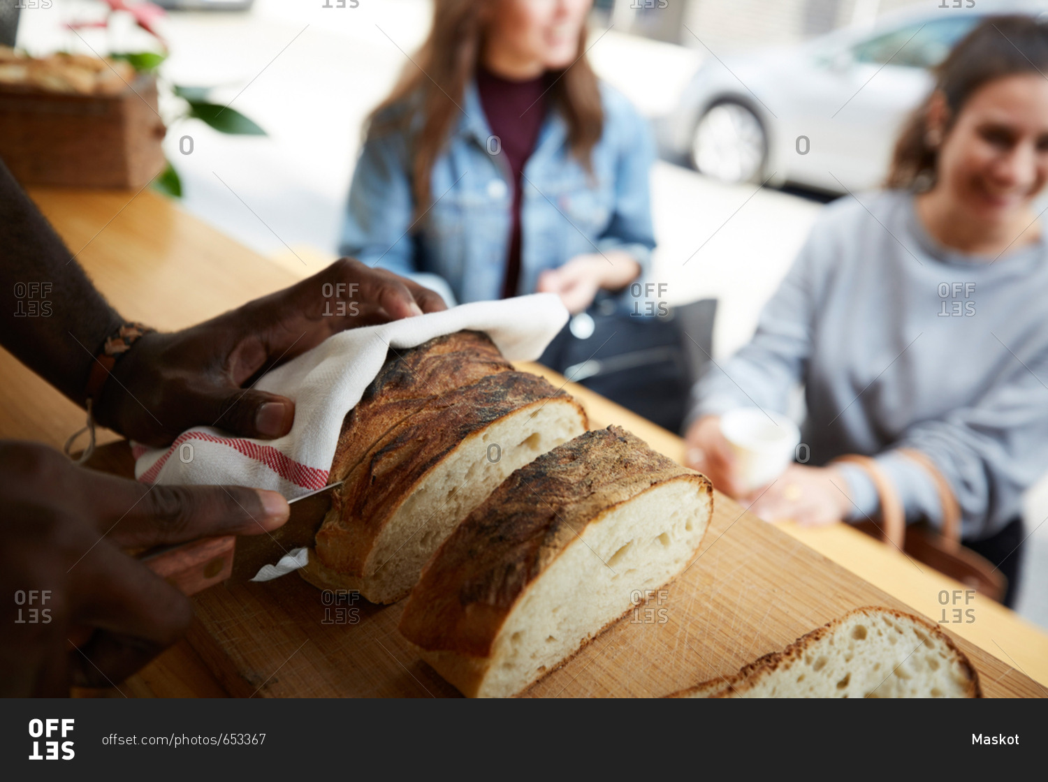 Cropped image of salesman cutting fresh bread for female customers at food truck