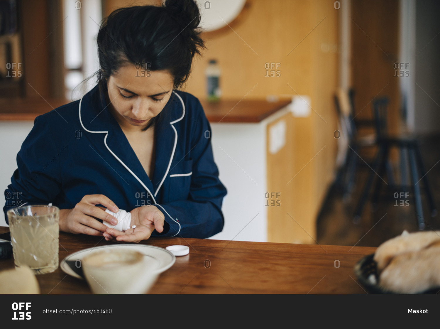 Woman taking medicine during breakfast while sitting at table