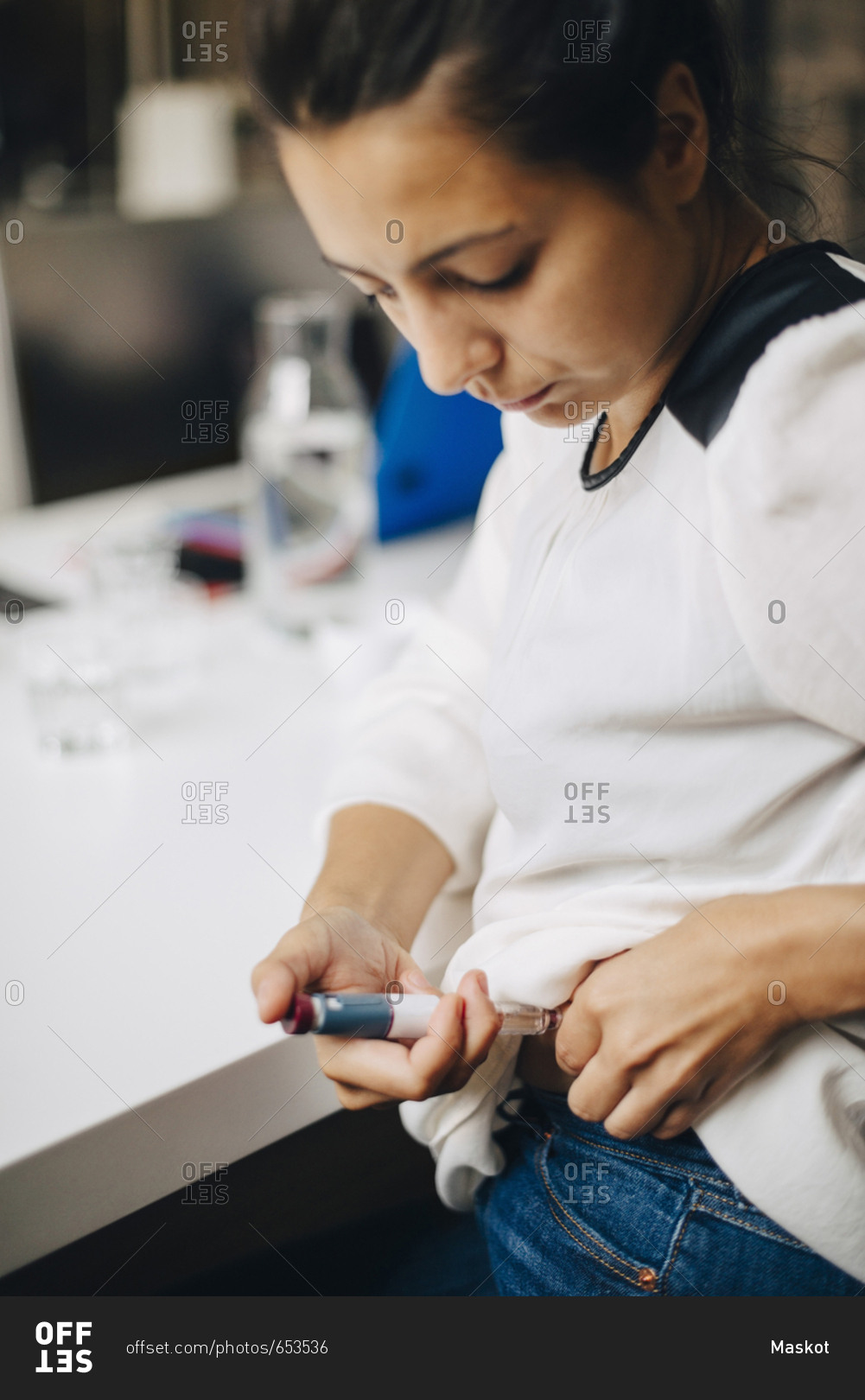 Businesswoman injecting insulin while sitting at table