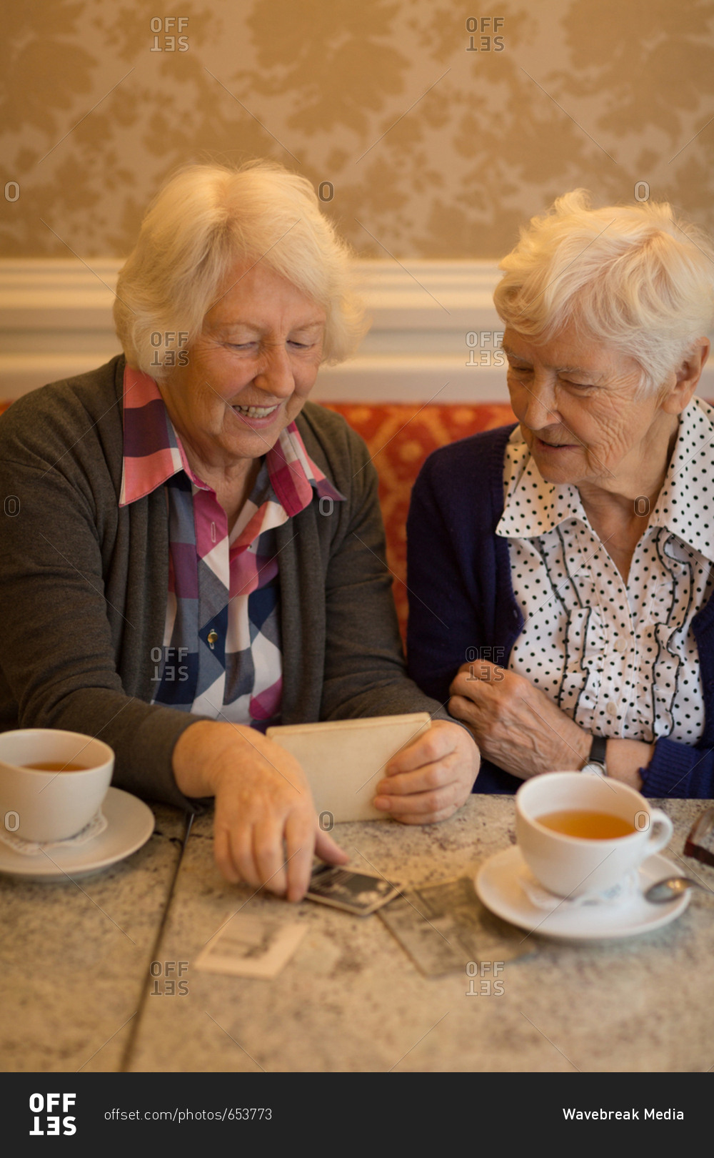 Senior friends interacting with each other while having coffee at home