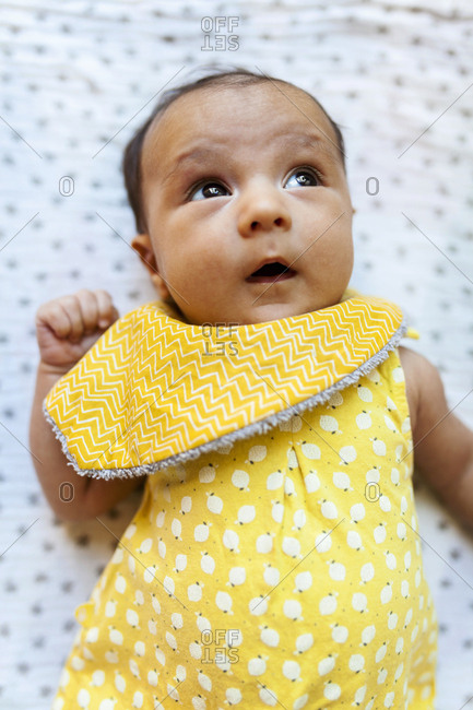 Curious baby in yellow looking up from crib