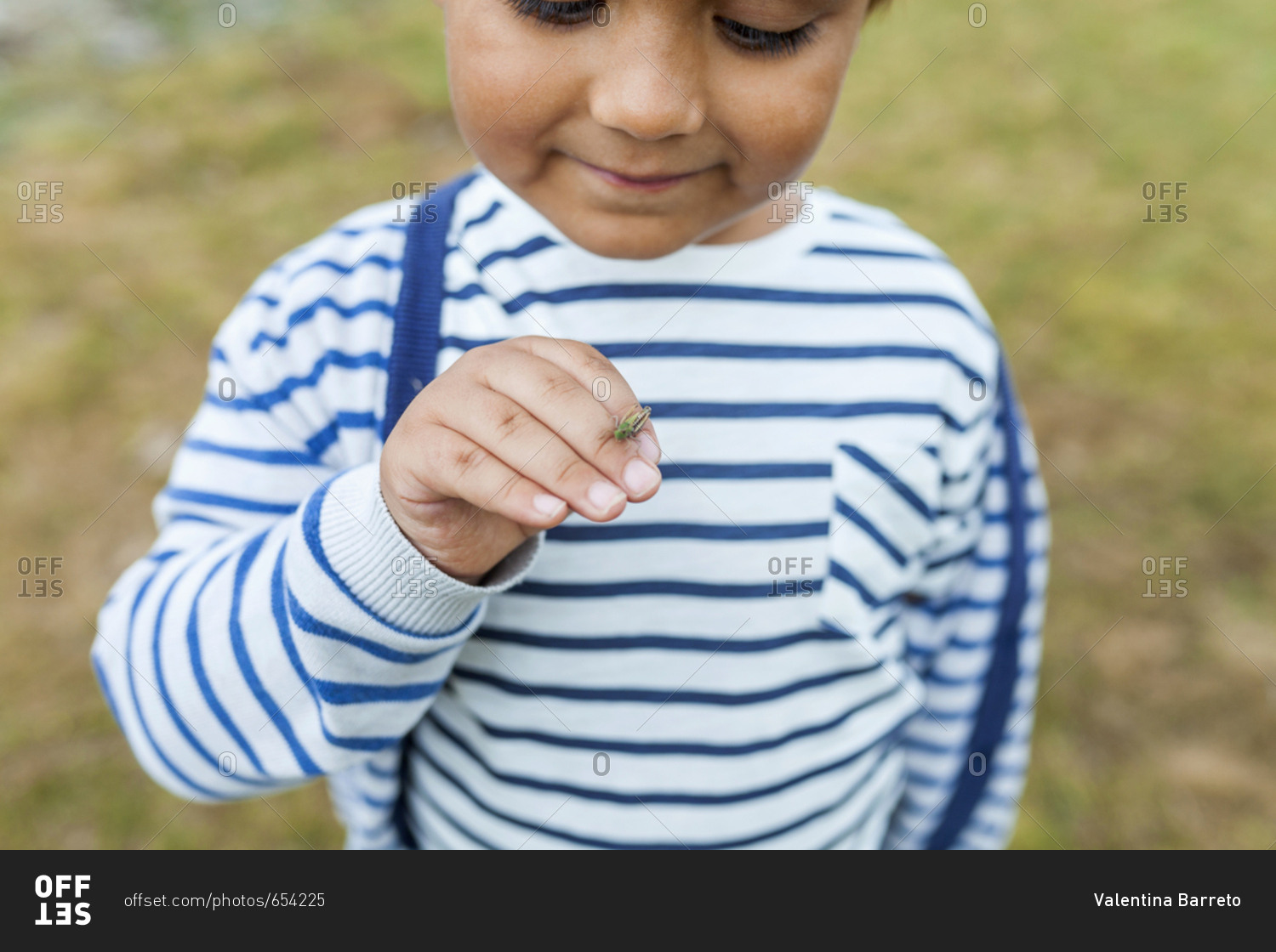 Little boy making friends with tiny cricket on hand