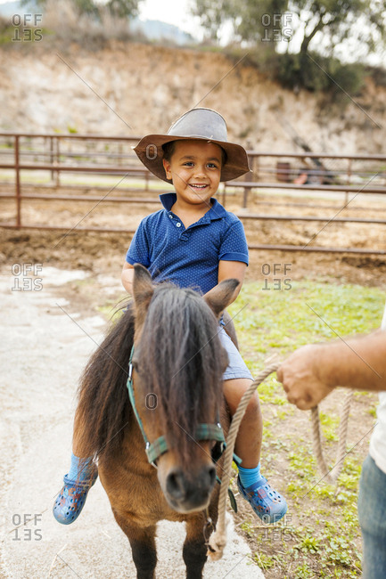 Download Little Boy In Leather Hat Riding Pony Stock Photo Offset
