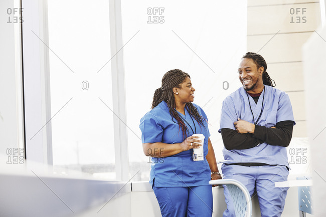 Happy male and female nurses talking while on coffee break