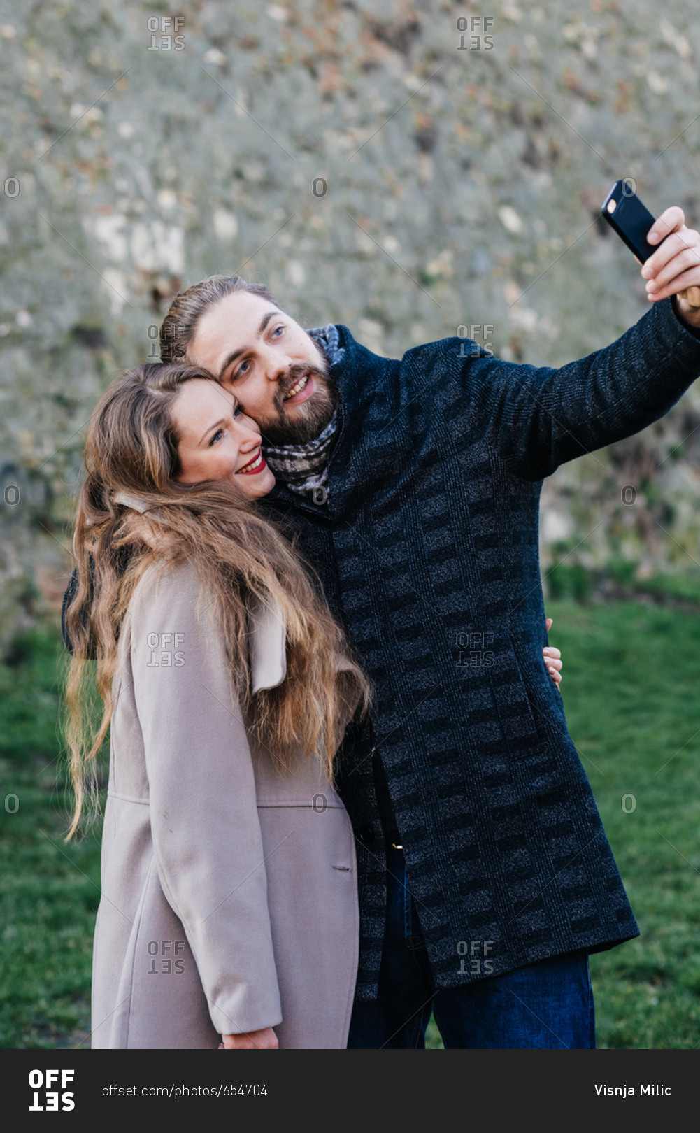 Beautiful couple hugging each other and making selfie photo with their phone camera