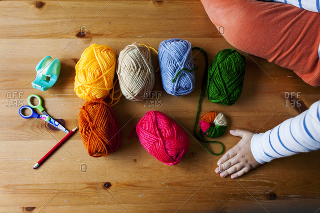 Overhead view of colorful balls of yarn and other materials for making pompoms