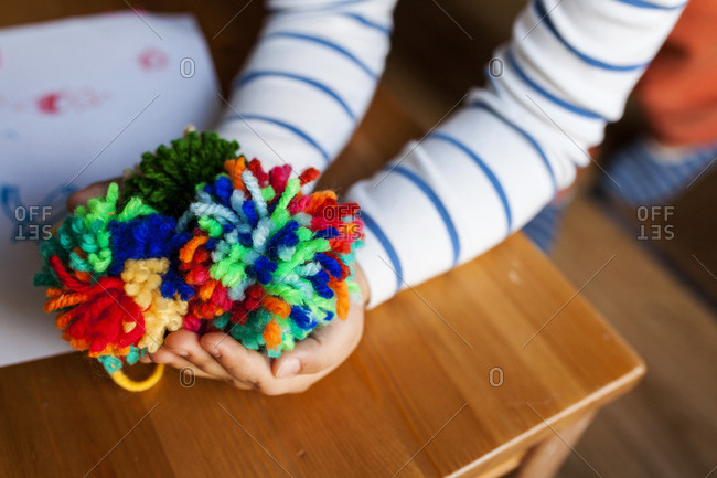 Pair of kid's hands showing off completed colorful pompoms