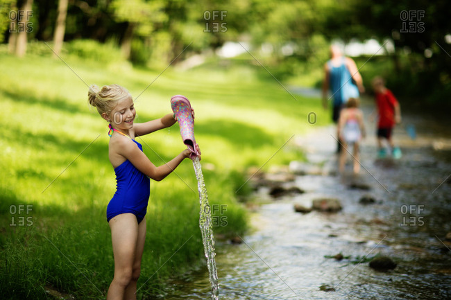 Girl pouring water out of boot in creek