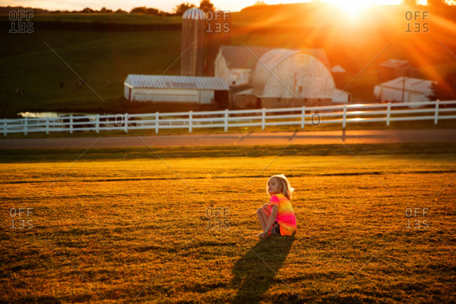 Girl sitting in front yard at sunset