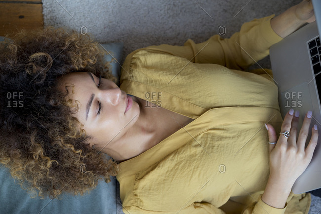 Young woman lying on the floor at home using laptop